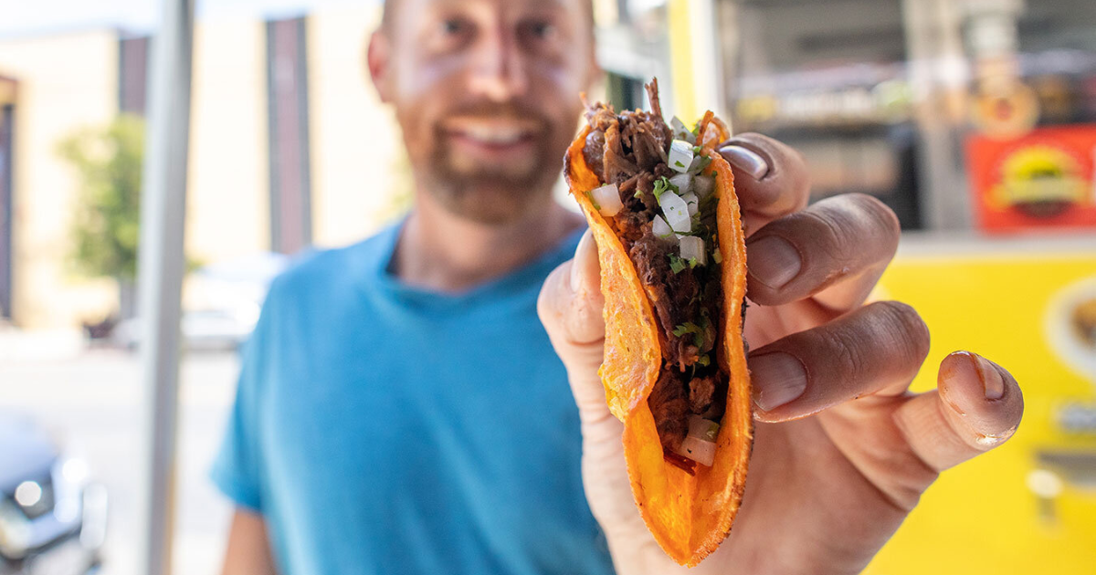 eric holding a taco at a food truck in san francisco backpacking and hiking