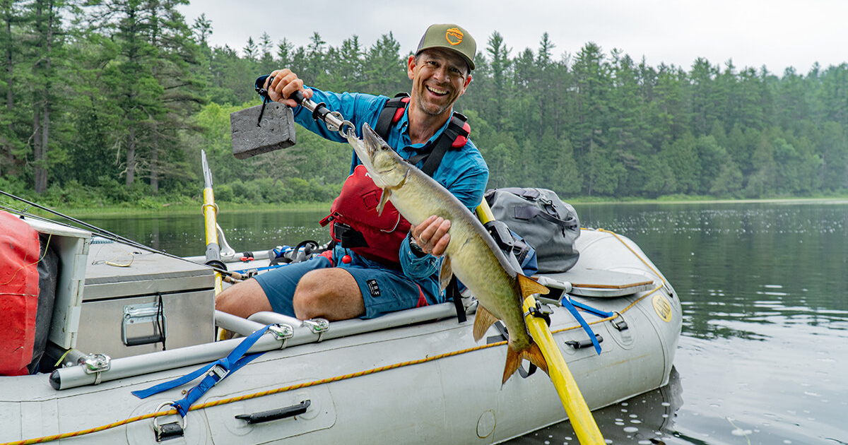 ken smiling with a musky in algonquin park on a kayak in the summer time fishing