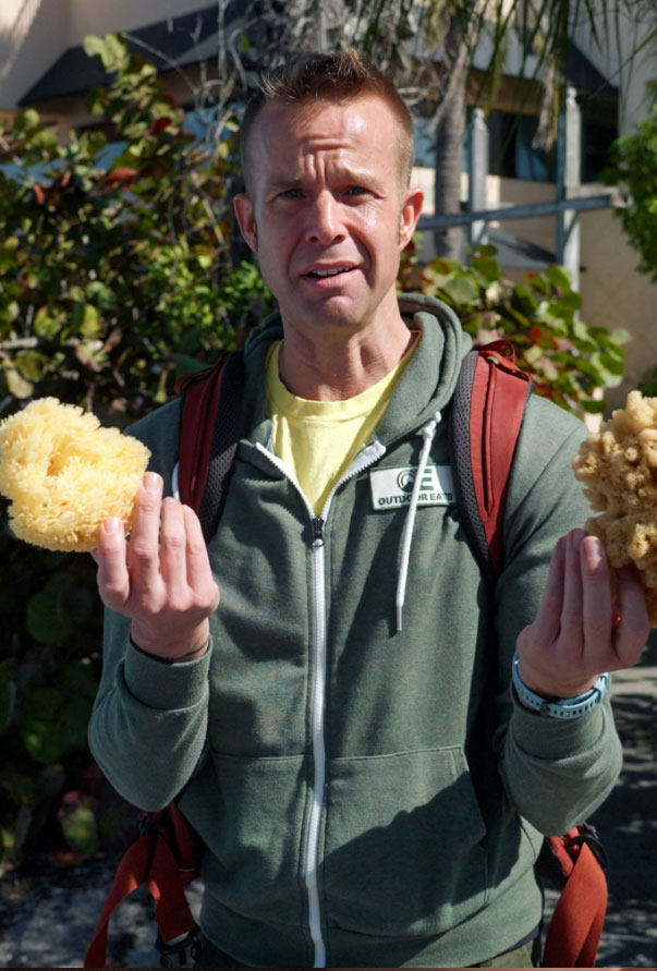 Host Chef Corso holding two natural sea sponges with quizzical look.