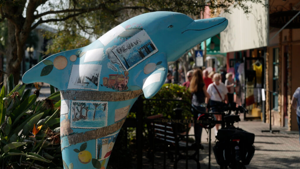 Statue of a dolphin covered in art/stickers.