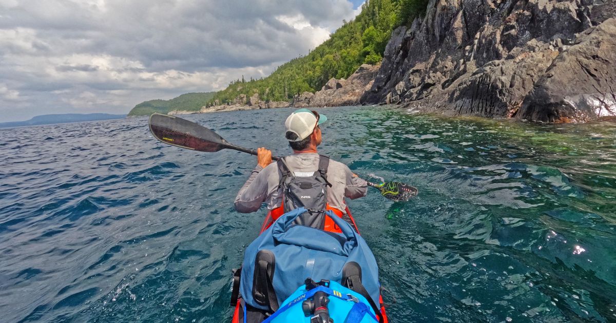 A kayak entering one of Lake Superior's dramatic sea caves, showcasing the region's unique natural features.