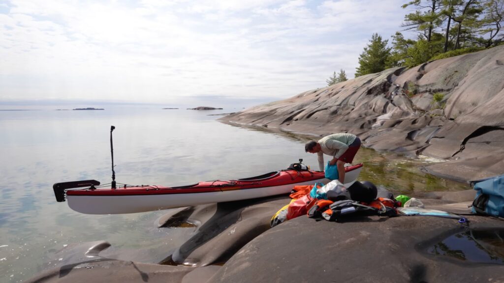 Boreal Designs Storm 17 kayak on granite rock, ken whiting packing his kayak on georgian bay kayak touring and camping trip